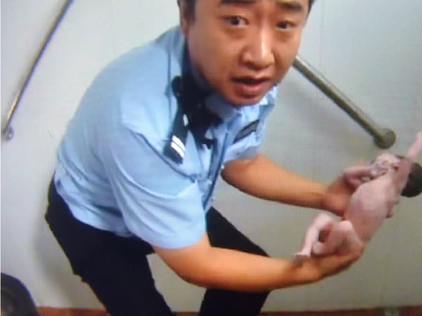 A screen capture of a Beijing Tianqiao Police video taken on Aug 2, 2015, which shows a Chinese policeman holding a newborn baby in a public toilet in Beijing. Photo: Beijing Tianqiao Police