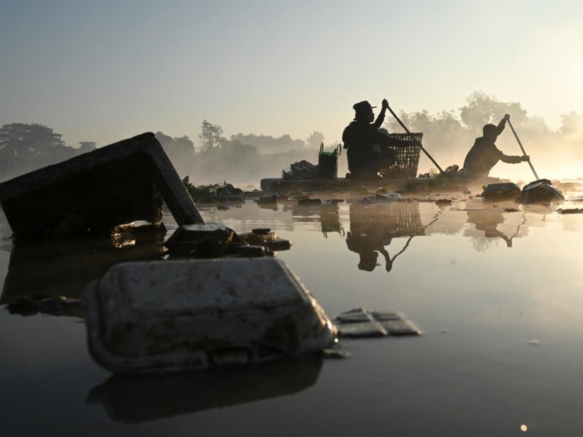 This photo taken on Jan 14, 2023 shows waste collectors paddling a polystyrene boat as they look for plastic and glass to recycle in Pazundaung Creek in Yangon. 