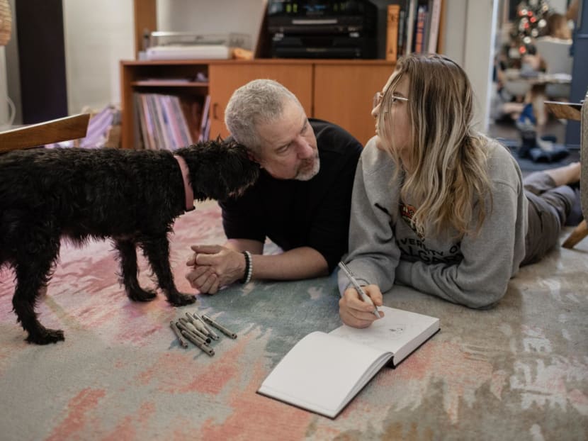 Aidan (right), who developed involuntary tics after watching videos on TikTok posted by teenagers claiming to have Tourette’s syndrome, with their father Norm and family dog Stella at home in Calgary, Canada, on Dec 18, 2022. 