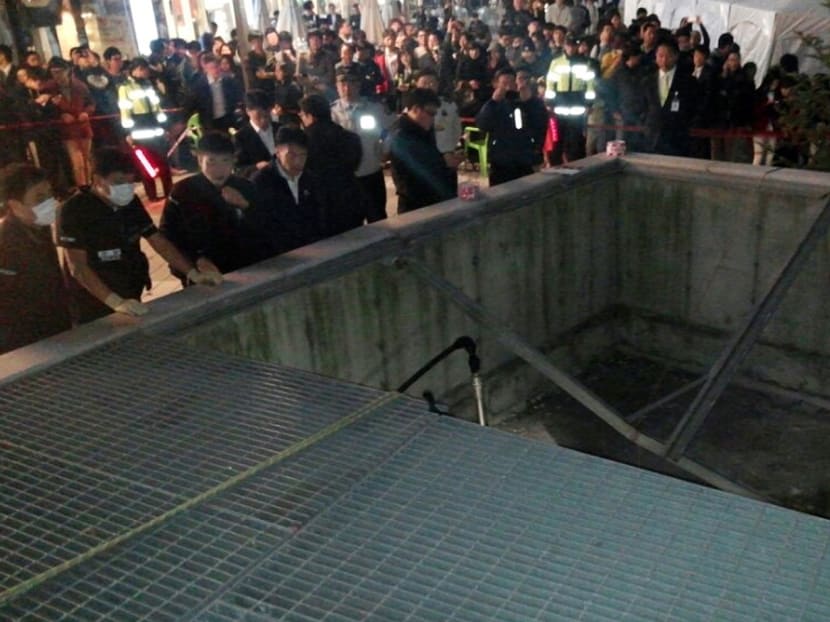 People gather around a collapsed ventilation grate at an outdoor theater in Seongnam, South Korea, Friday, Oct. 17, 2014. Officials say that two people have died and 12 others were presumed dead after a ventilation grate near an outdoor concert venue collapsed. Photo: AP