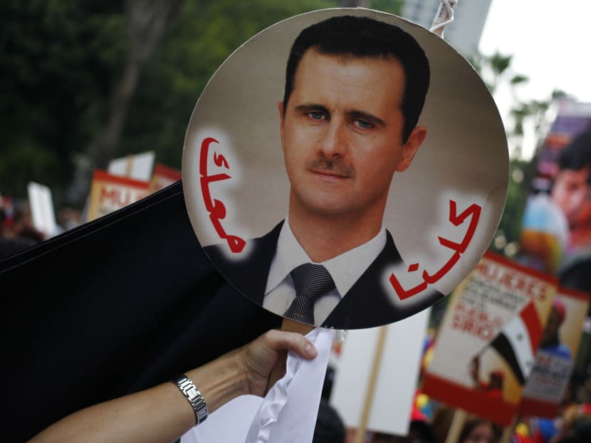 A Syrian-Venezuelan holds up a poster of Syrian President Bashar al-Assad. Photo: REUTERS
