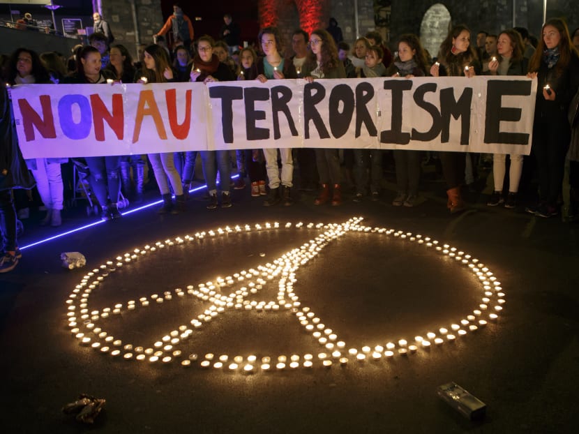 In this Nov 14, 2015 picture people gather around a peace sign with  Eiffel  Tower,  realized by candles, during a rally  for the victims of the terrorist attacks in Paris, in Lausanne, Switzerland. Banner in French reads : No to terrorism. Photo: Keystone via AP