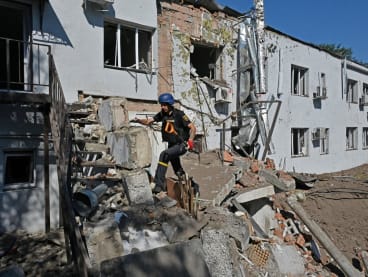 A Ukrainian deminer climb debris near the damaged building of a clinical medical laboratory following a Russian rocket strike in the second largest Ukrainian city of Kharkiv on Aug 9, 2022.