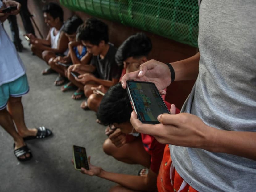 Youngsters use their mobile phones to play Axie Infinity, an NFT game where players earn tokens that can be exchanged for cryptocurrency or cash on Dec 15, 2021.