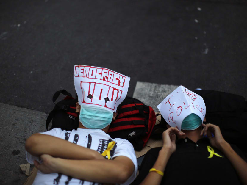 Pro-democracy protesters lie on the ground as they block an area near the government headquarters building in Hong Kong Oct 14, 2014. Photo: Reuters