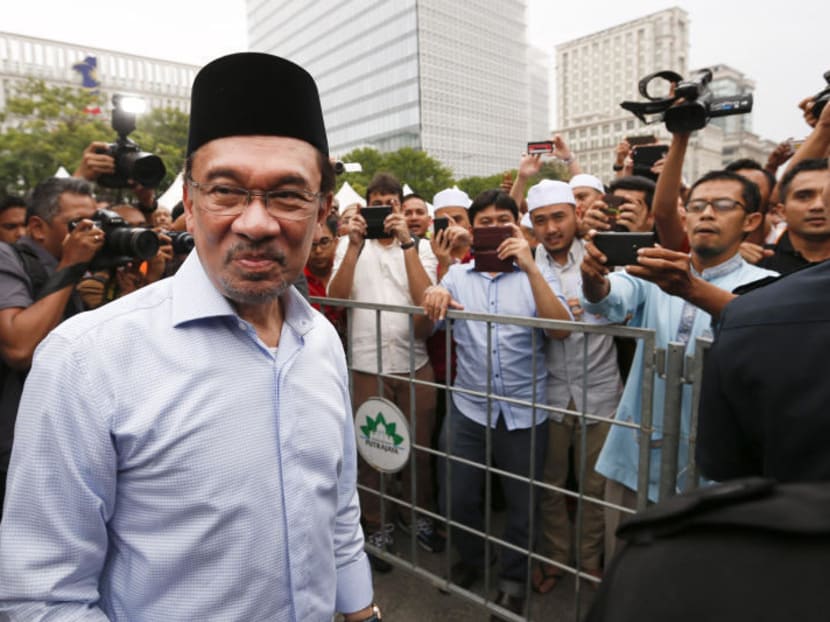 In this Nov 7, 2014 file photo, Malaysian opposition leader Anwar Ibrahim, left, is greeted by his supporters as he returns from a Friday prayer to a court house during the final hearing of his sodomy conviction in Putrajaya, Malaysia. Photo: AP