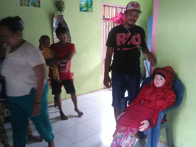 This recent undated handout picture released by Indonesian police and made available on May 3, 2016 shows an Indonesian man standing next to a sex doll (R-on chair) at a home in Banggai in Sulawesi. Photo: AFP