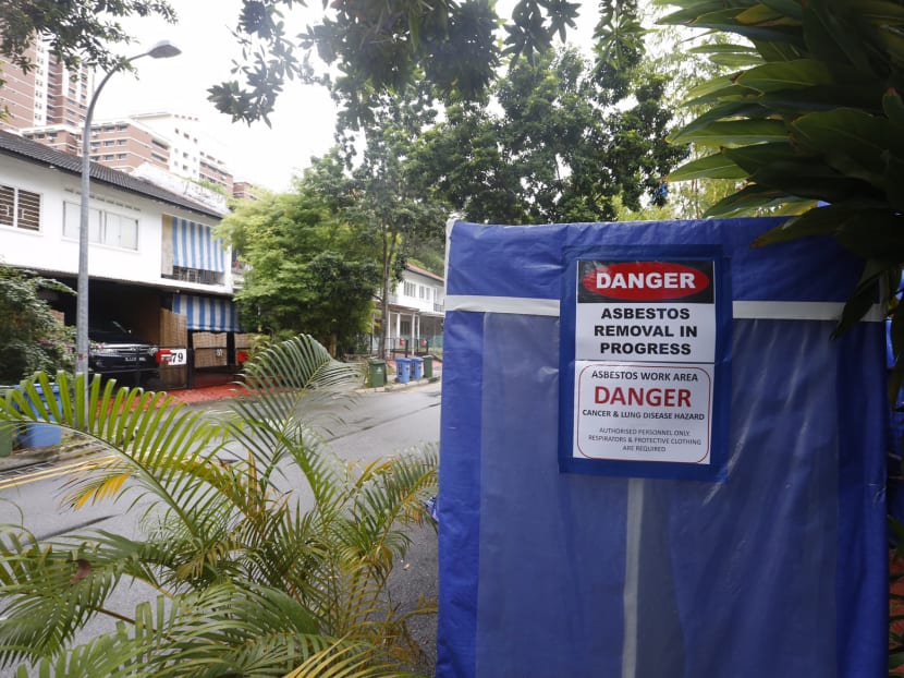 The front sections of two units along Jalan Hitam Manis in Chip Bee Gardens covered in blue tarp with signs indicating asbestos removal. Photo: Raj Nadarajan/TODAY