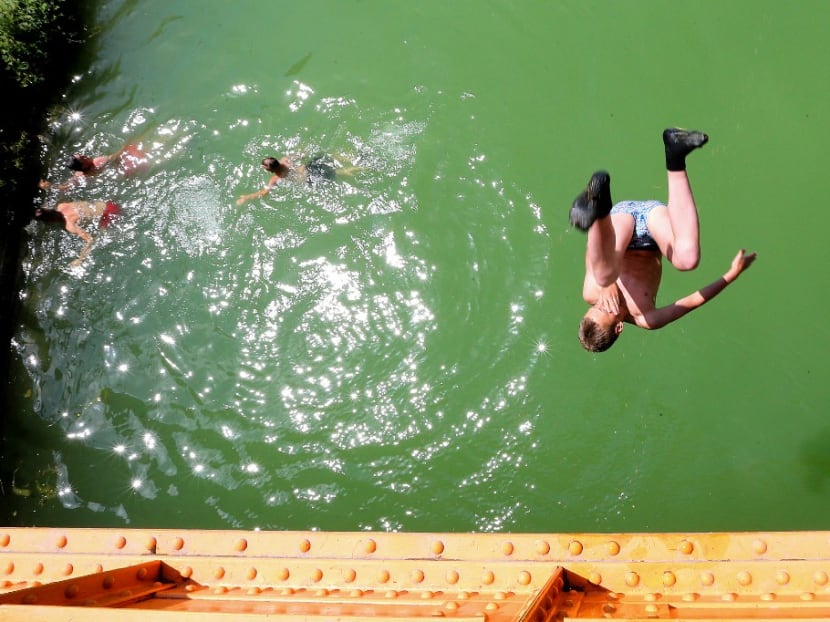 In this file photograph taken on June 25, 2019, youth jump into a canal near Reims, north-eastern France, as temperatures soar which meteorologists are blaming on a blast of torrid air from the Sahara for an unusually early summer heatwave.