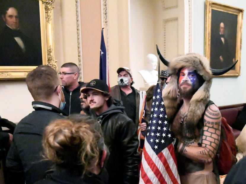Jacob Anthony Chansley, also known as Jake Angeli, of Arizona, stands with other supporters of US President Donald Trump as they demonstrate on the second floor of the US Capitol near the entrance to the Senate after breaching security defences in Washington, US on Jan 6, 2021.