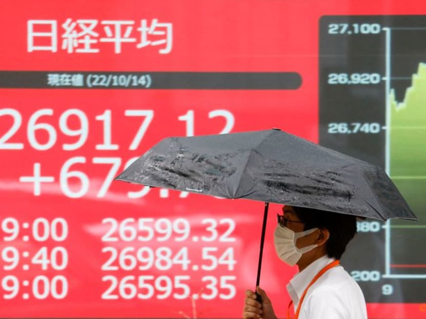 FILE PHOTO: A man walks past in front of an electric monitor displaying the Japanese Nikkei share average in Tokyo, Japan October 14, 2022 REUTERS/Issei Kato FILE PHOTO: A man walks past in front of an electric monitor displaying the Japanese Nikkei share average in Tokyo, Japan October 14, 2022 REUTERS/Issei Kato