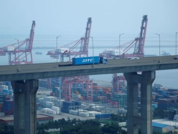 FILE PHOTO: A truck carrying a shipping container travels past cranes at Pyeongtaek port in Pyeongtaek, South Korea, July 9, 2020.    REUTERS/Kim Hong-Ji/File Photo
