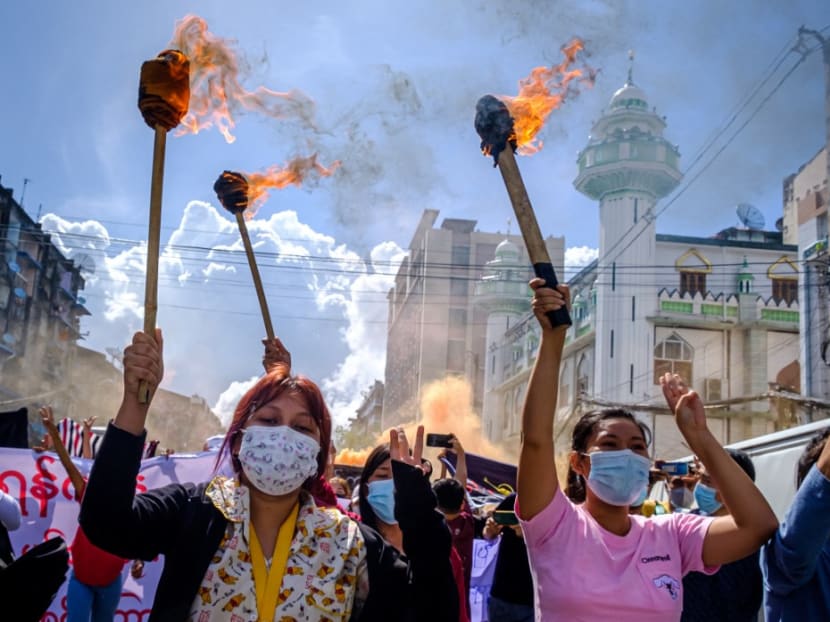 Women carry burning torches as they march during a demonstration against the military coup in Yangon on July 14, 2021.