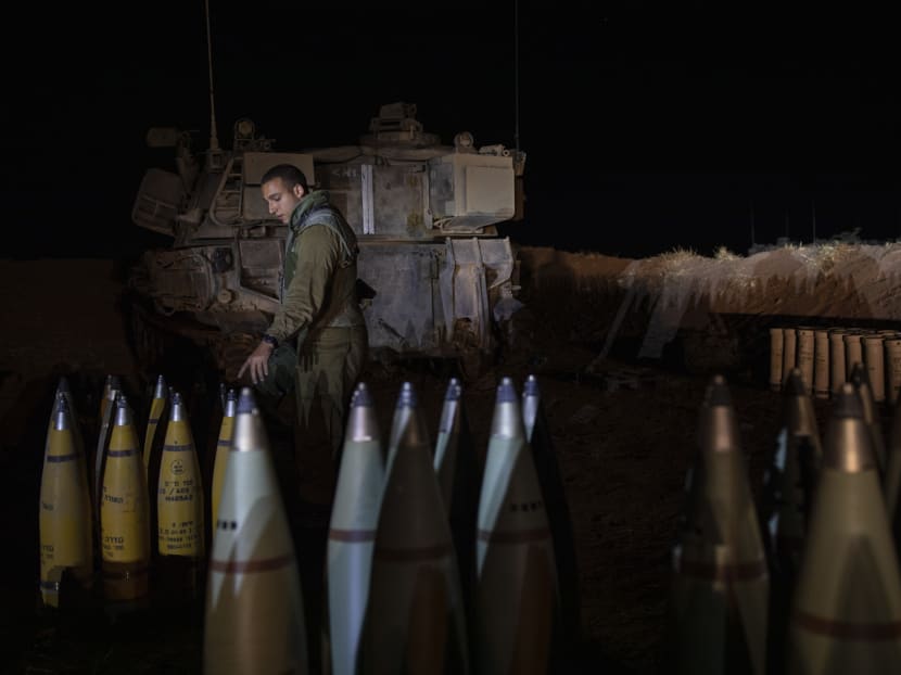 An Israeli soldier reaches out to an artillery shell in Israel, near the border with Gaza Strip on Tuesday evening, May 18, 2021.