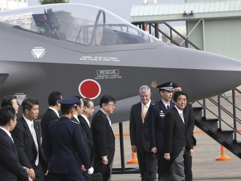 In this Oct 26, 2014 file photo, Japanese Prime Minister Shinzo Abe, right, walks by a mock-up of the F-35 fighter jet during the annual Self-Defense Forces Commencement of Air Review at the Hyakuri Air Base, north of Tokyo. Photo: AP
