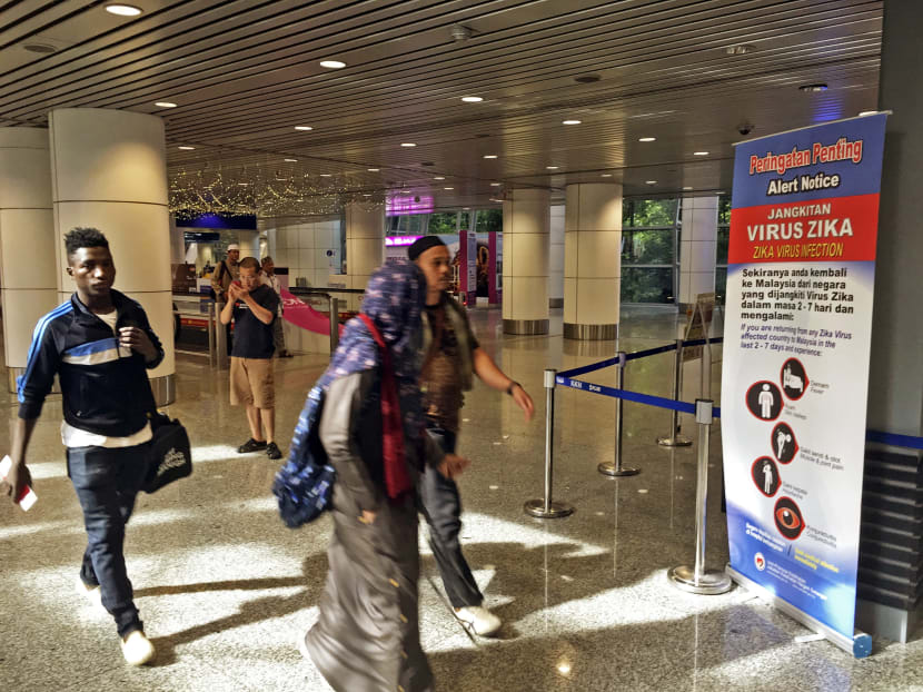 Travellers walk past a travel advisory on the Zika virus infection in Kuala Lumpur International Airport (KLIA) in Sepang, Malaysia, Aug 28, 2016. Photo: AP