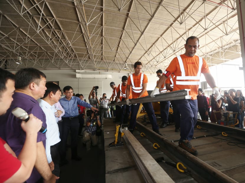 Coordinating Minister for Infrastructure and Minister for Transport, Mr Khaw Boon Wan (third from left, in the light blue shirt), seen here viewing a demonstration of the power rail replacement at SMRT's Bishan Depot. Photo: Koh Mui Fong/TODAY