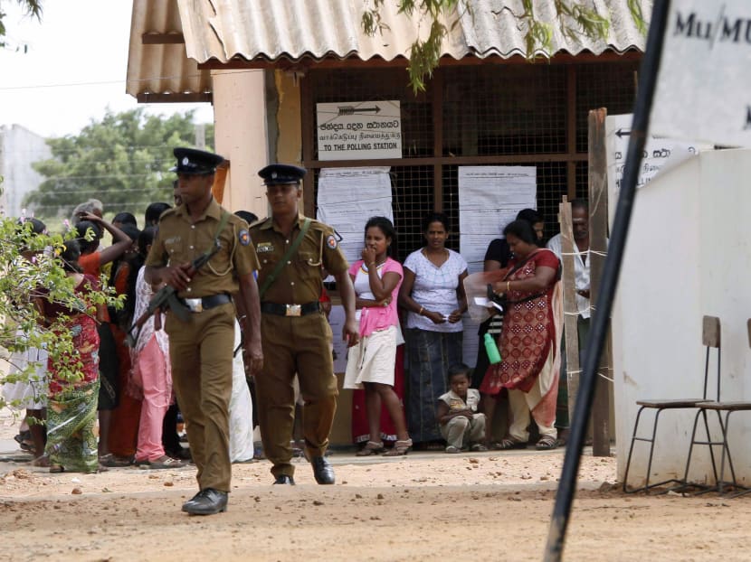 Sri Lankan Tamils stand in a queue to cast their vote as police officers keep vigil outside a polling station in the former war zone region of Mullaitivu, Sri Lanka, Saturday, Sept. 21, 2013 .Photo: AP