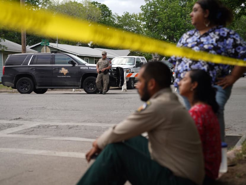 People sit on the curb outside of Robb Elementary School as State troopers guard the area in Uvalde, Texas, on May 24, 2022 after an 18-year-old gunman killed 14 children and a teacher.
