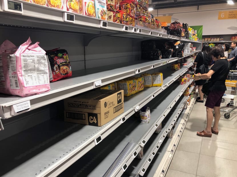 A customer at Fairprice Finest in Bukit Timah Plaza looking at a shelf that was nearly emptied of flour.