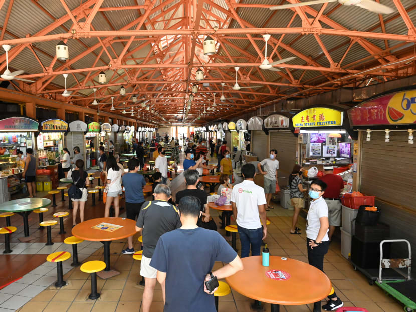 People, wearing face masks as a preventive measure against the spread of Covid-19, queue to buy food at a hawker centre in Singapore on May 14, 2020.