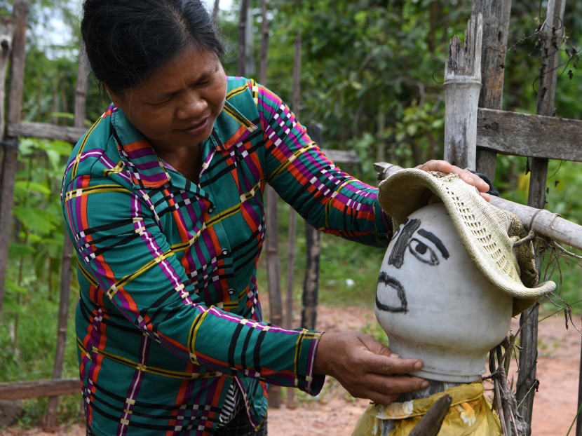 A woman sets up a scarecrow in front of her home in Cambodia's Kampong Cham province on October 11, 2020, as superstitious residents in the region set up the sentries known as "Ting Mong" in Khmer to ward off Covid-19 during the pandemic.