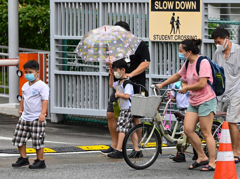 Children walk home with their guardians after school in Singapore on May 17, 2021.