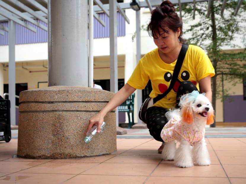 Yishun resident Jennifer Lim, 51, demonstrates using a water bottle to clean up dog urine, as her dog Xuemin looks on, in Yishun on Oct 9, 2016. Photo: Jason Quah