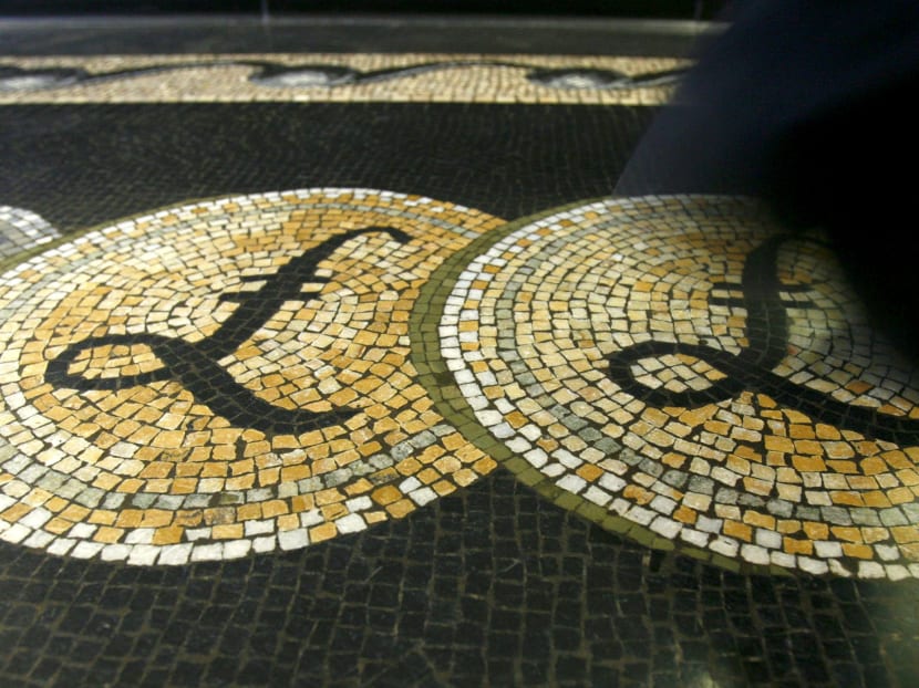 An employee is seen walking over a mosaic of pound sterling symbols set in the floor of the front hall of the Bank of England in London, March 25, 2008. Photo: Reuters