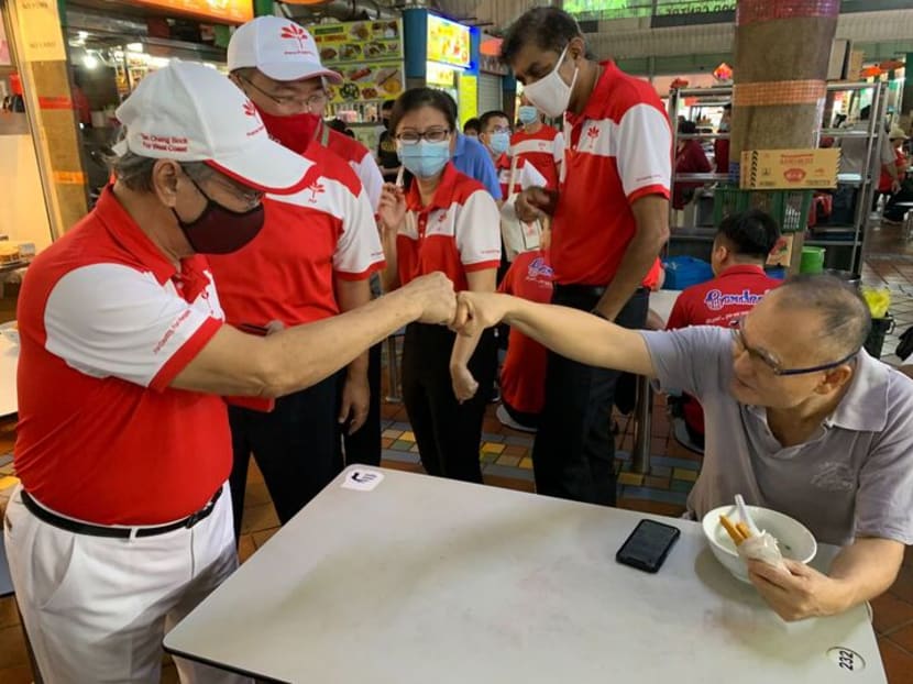 Dr Tan Chong Bock (left) fist-bumping a resident at Ayer Rajah Market, accompanied by his West Coast GRC team, on July 12, 2020.
