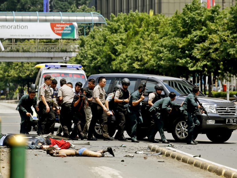 Dead bodies on the ground as Indonesian police walk behind a car for protection in Jakarta on Jan 14, 2016. Besides five attackers, a police officer and a Canadian man were killed. Photo: Reuters