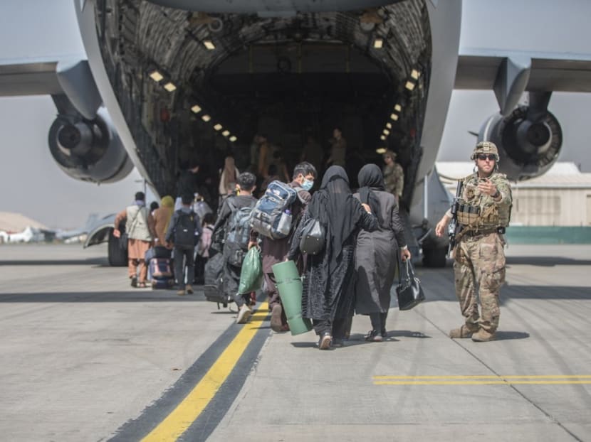In this handout image courtesy of the US Marine Corps, families begin to board a US Air Force Boeing C-17 Globemaster III during an evacuation at Hamid Karzai International Airport, Kabul, Afghanistan on Aug 23, 2021.