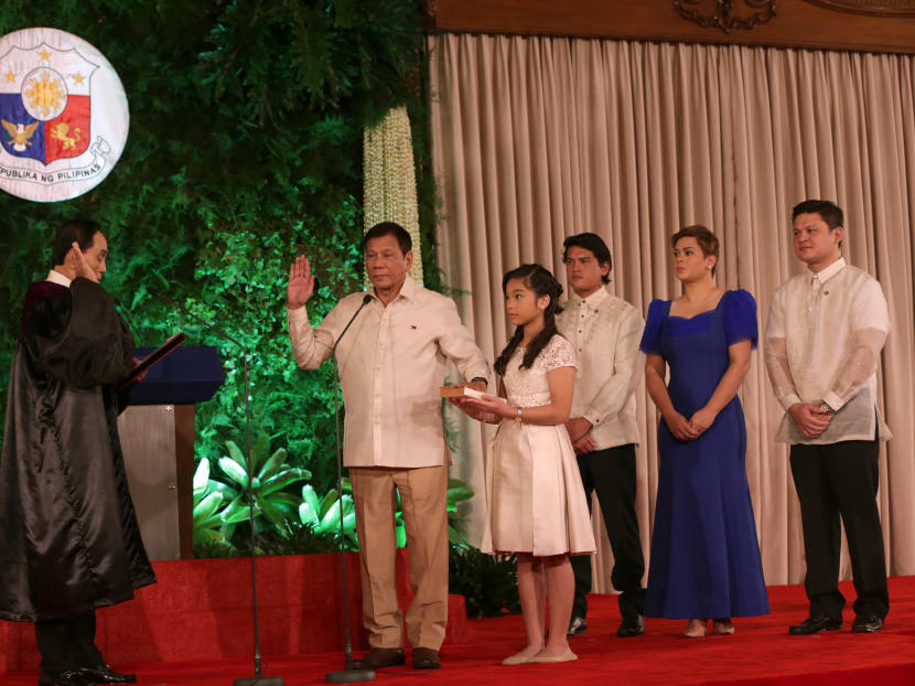 President Rodrigo Duterte is sworn-in by Supreme court associate justice Bienvenido Reyes while his daughter Veronica Duterte holds the bible and other children (back L-R) Sebastian Duterte, Sara Duterte and Paolo Duterte look on during the oath-taking ceremony at the Malacanang Palace in Manila. Photo: Presidential Communication Operations Office via AFP