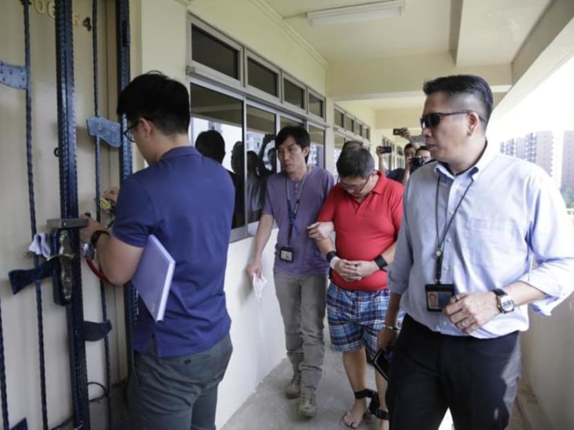 Teo Ghim Heng being led to the door of the flat in Woodlands where he killed his pregnant wife and daughter. The court heard Teo viewed pornography almost every day in the weeks before the killings..