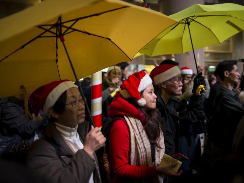 Pro-democracy protesters, holding up yellow umbrellas, a symbol of the Occupy Central civil disobedience movement, attend a protest at Times Square in Hong Kong early December 25, 2014. Hundreds of people gathered before midnight on Christmas eve calling for universal suffrage and for Beijing to withdraw its decision on political reform. According to local media, the demonstration is among a series of events including flash mob protests and singing of Christmas carols, as an extension of the Occupy movement.  Photo: Reuters