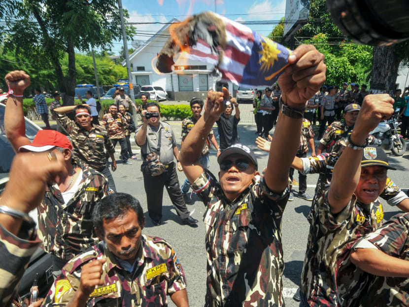 Protesters tearing, burning and holding upside-down a replica of the Malaysian national flag during an anti-Malaysia rally in front of its consulate office in Medan in North Sumatra. Photo: AFP