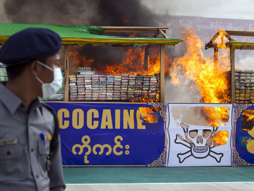 Myanmar police officer stands while smokes and flames billow from burning drugs during a destruction ceremony of seized narcotic drugs in outskirts of Yangon. Photo: AP