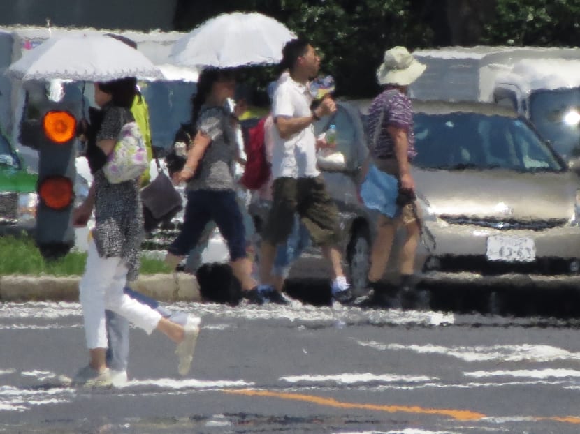 The effects of heat haze is seen in this photograph as pedestrians cross a street during a heatwave in Tokyo. Government data shows the heatwave has sent more than 70,000 people to hospitals across the country over the last three months.