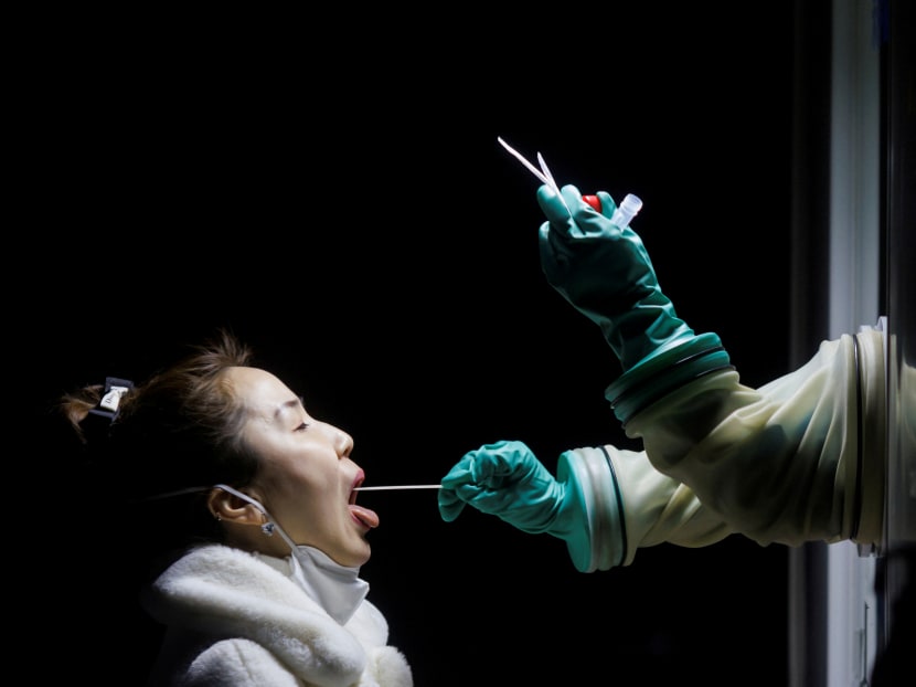 A woman receives a throat swab test at a street booth as the coronavirus disease (COVID-19) pandemic continues in Beijing, China, on Jan 17, 2022.