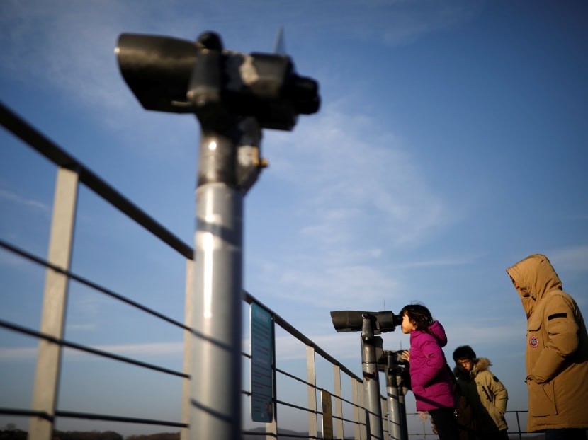 A girl looks toward the North through a pair of binoculars near the demilitarised zone separating the two Koreas in Paju, South Korea. The author says humiliating Pyongyang over its intent to join next month's Winter Olympics would be a mistake. Photo: Reuters