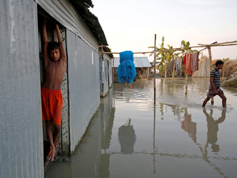 A boy stands in the door of his flooded house in Bogra, Bangladesh, August 20, 2017. Photo: Reuters
