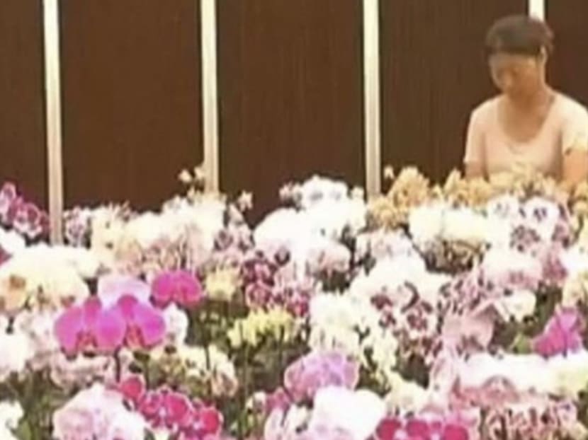 A woman stands beside a display of colourful orchids. Photo: South China Morning Post/Handout