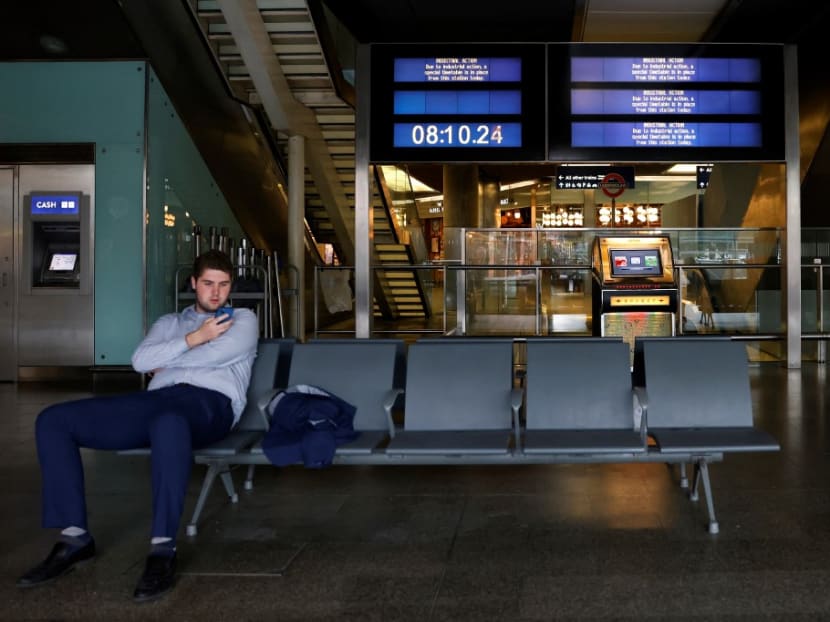 A commuter looks at a mobile phone in front of screens informing travellers of an industrial action at King's Cross railway station in London on July 27, 2022 as fresh railway strikes hit the country. A commuter looks at a mobile phone in front of screens informing travellers of an industrial action at King's Cross railway station in London on July 27, 2022 as fresh railway strikes hit the country.