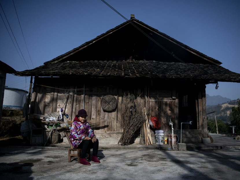 A woman sits in front of her residence in Baojing County, in central China's Hunan province on Jan 12, 2021.