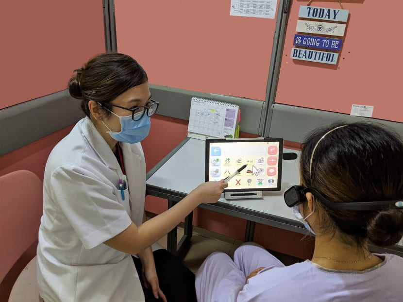 A senior speech therapist at Tan Tock Seng Hospital training a patient to communicate using an eye-gaze tracking sensor.