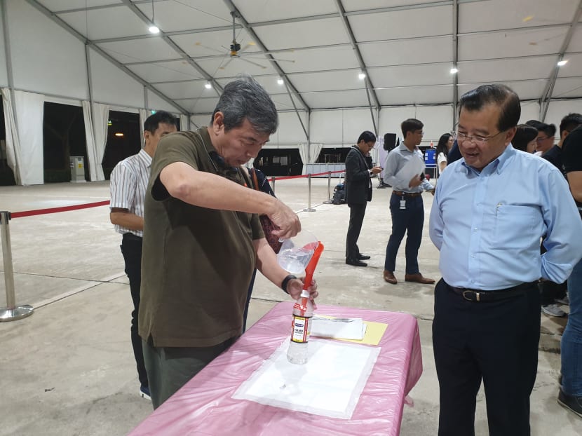 Mr Lim Hock Chuan, chief executive of Temasek Foundation Ecosperity and Temasek Foundation Connects (right) looks on as a volunteer fills a reusable bottle with free hand sanitiser at a training session for volunteers at Pasir Ris Elias Community Centre on March 17, 2020.