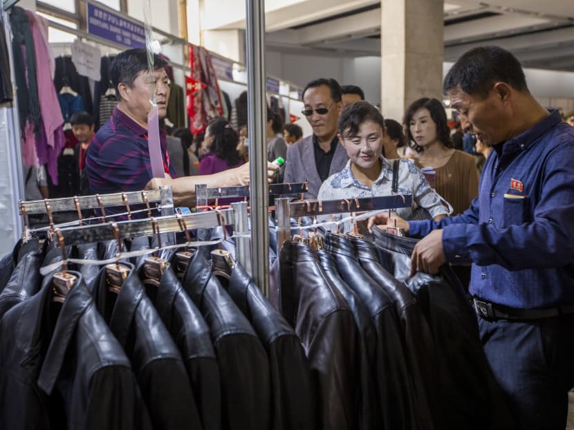 A Chinese salesman (left) selling leather jackets at the 14th Pyongyang Autumn International Trade Fair on Sept 20, 2018.