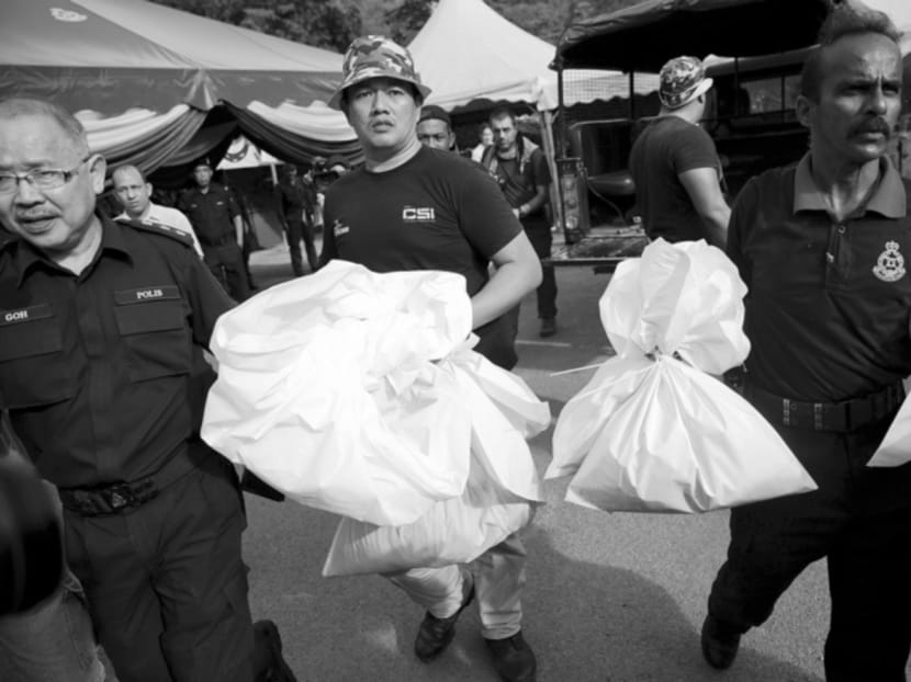 Malaysian forensic police officers carrying body bags with human remains found at the site of human trafficking camps in the jungle close to the Thailand border in May last year. Photo: Reuters
