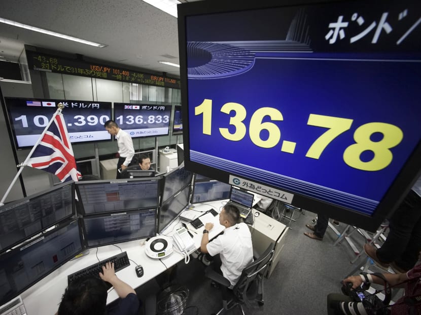 Money traders monitor computer screens with the day's exchange rate near flags of United Kingdom and Eu at a foreign exchange brokerage at a securities firm in Tokyo, Friday, June 24, 2016. Photo: AP