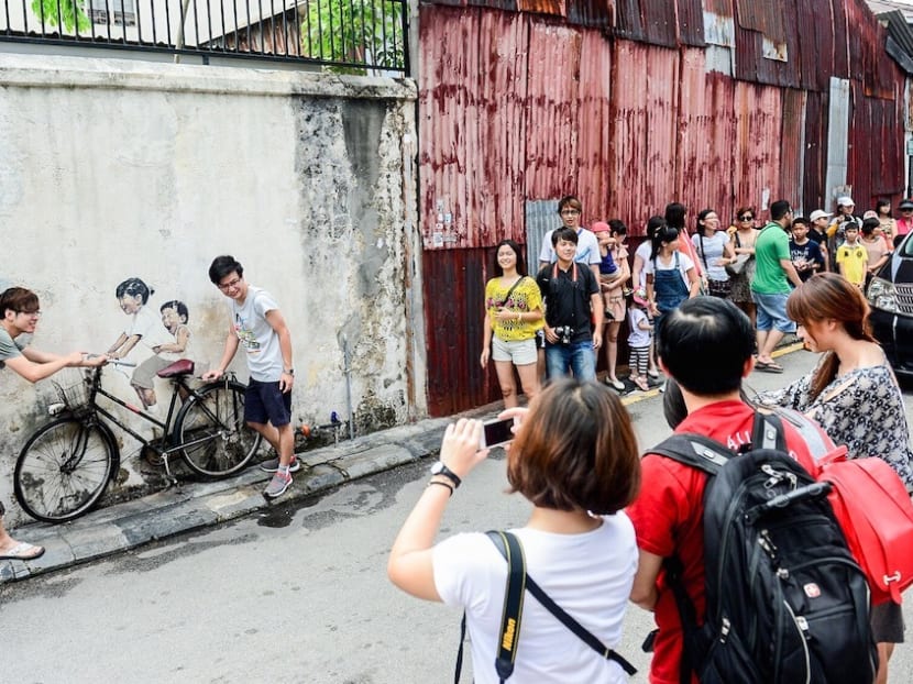 Tourists line up to take photos with the famous Little Children on a Bicycle mural by Ernest Zacharevic at Lorong Armenian in Georgetown.